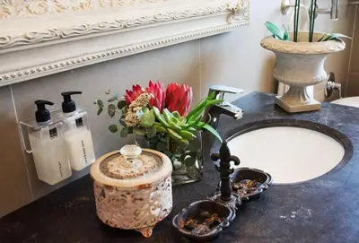 a bathroom counter with a sink and a vase with flowers at Avemore Lagratitude no6 - with full backup power in Stellenbosch