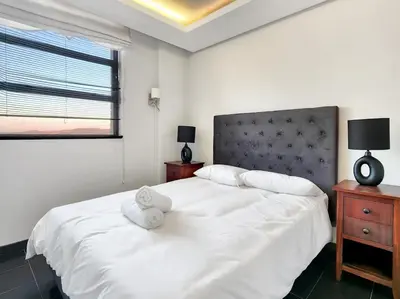 a bedroom with a white bed with two towels on it at Bird's View in Cape Town