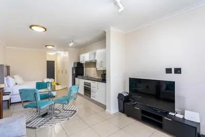 a kitchen and living room with a table and chairs at Waterstone A202 by CTHA in Cape Town