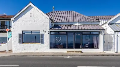 a white house with a metal roof on a street at 59 Marine Hermanus in Hermanus
