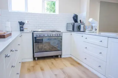 a white kitchen with a stove and a microwave at 5BR Pool Fast Wi-Fi Walk To The Beach Pool Table in Cape Town