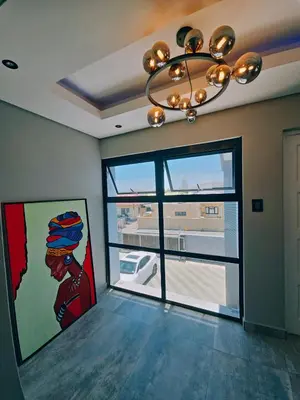 a room with a large window and a chandelier at Beachwalk luxury one bedroom apartments in Cape Town