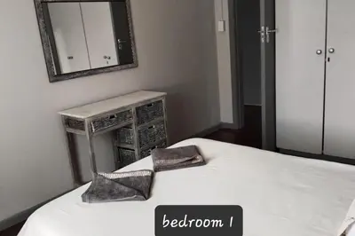 a bedroom with a bed with two pillows and a mirror at strand Holiday House in Strand