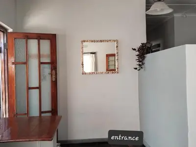 a mirror on a wall next to a refrigerator at strand Holiday House in Strand