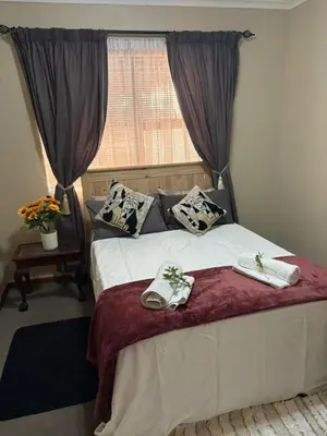 a bedroom with a bed with two towels on it at Waaigras in Brackenfell