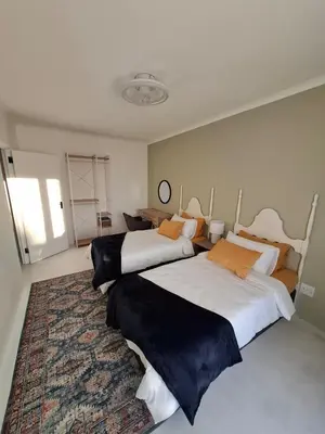 two beds in a large room with a rug at Embrace This Planet Self-Catering Accommodation in Fisherhaven