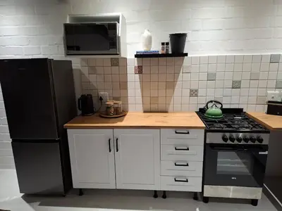a kitchen with white cabinets and a black refrigerator at Embrace This Planet Self-Catering Accommodation in Fisherhaven