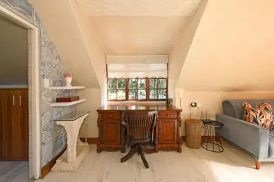 a living room with a desk and a couch at Mawethu on Mead Guesthome with Covered pool and Garden in Cape Town