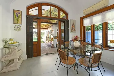 a dining room with a glass table and chairs at Mawethu on Mead Guesthome with Covered pool and Garden in Cape Town