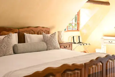 a bedroom with a large bed with pillows at Mawethu on Mead Guesthome with Covered pool and Garden in Cape Town