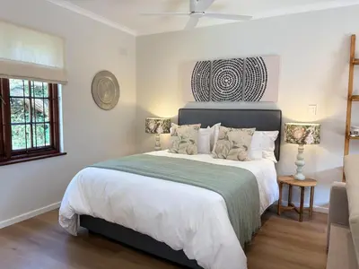 a bedroom with a large bed with a green blanket at Protea Cottage Cozy & Private Studio in Claremont in Cape Town
