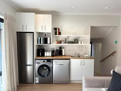 a kitchen with a refrigerator and a washing machine at Protea Cottage Cozy & Private Studio in Claremont in Cape Town