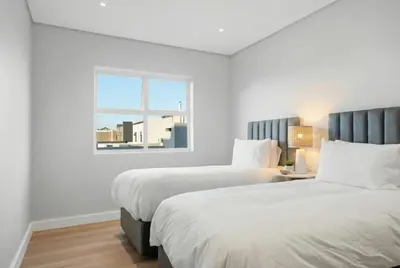 two beds in a white room with a window at Cape Signature Villa in Cape Town