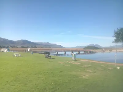 a bridge over a body of water with a grass field at Starfish Cottage in Kleinmond