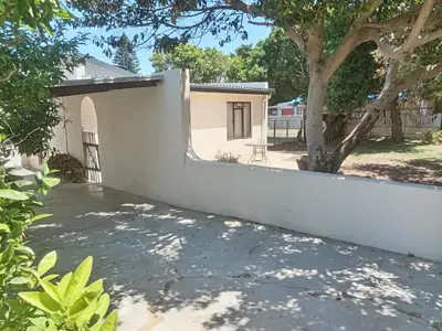 a white wall with a tree in front of a house at Starfish Cottage in Kleinmond