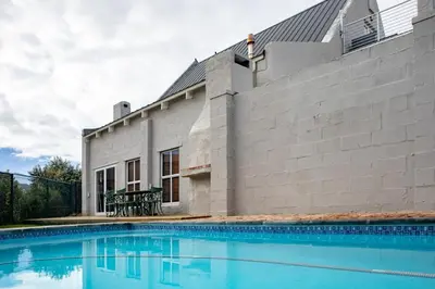 a house with a swimming pool in front of a building at Joan's Sea Cottage in Pringle Bay
