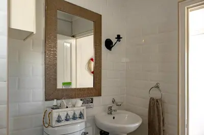 a white bathroom with a sink and a mirror at Joan's Sea Cottage in Pringle Bay
