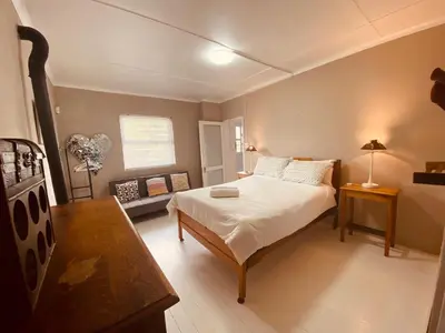 a bedroom with a bed and a table and a couch at Joan's Sea Cottage in Pringle Bay