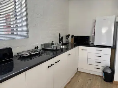 a kitchen with white cabinets and a black counter top at Layover on Loerie in Cape Town