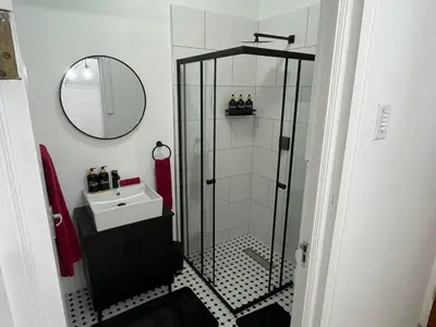 a bathroom with a shower with a sink and a mirror at Layover on Loerie in Cape Town