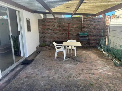 a table and two chairs on a brick patio at Layover on Loerie in Cape Town