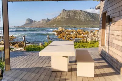 a white bench on a deck with a view of the ocean at Pringle Bay Beach Cottage in Pringle Bay