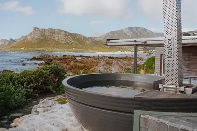 a large hot tub on a patio next to the water at Pringle Bay Beach Cottage in Pringle Bay