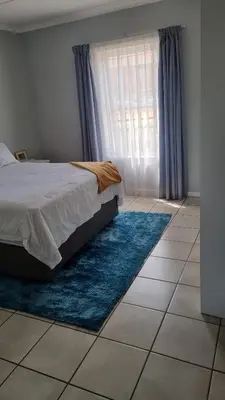 a bedroom with a bed and a window with blue rugs at Riley's Place in Cape Town