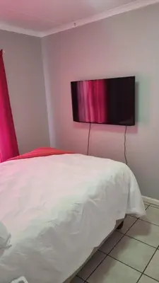 a bedroom with a bed and a television on the wall at Riley's Place in Cape Town