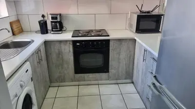 a small kitchen with a stove and a sink at Riley's Place in Cape Town