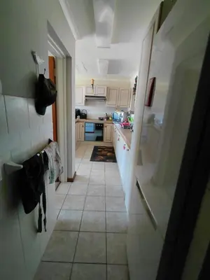 a kitchen with white cabinets and a tile floor at HuisieBydieC in Hermanus