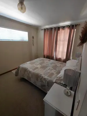 a bedroom with a bed and a window with a lamp at HuisieBydieC in Hermanus