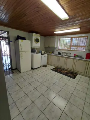 a kitchen with white appliances and a wooden ceiling at HuisieBydieC in Hermanus
