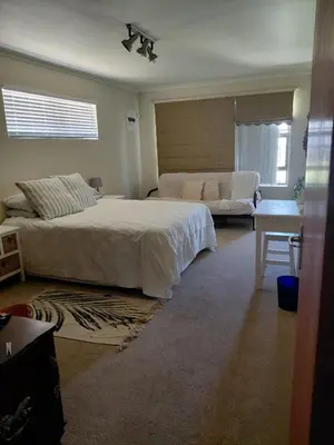 a bedroom with a large bed and a couch at HuisieBydieC in Hermanus