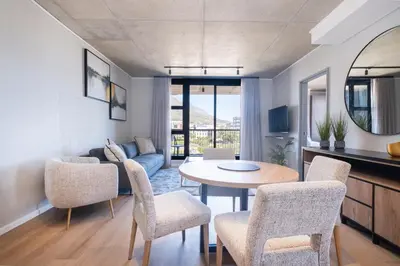 a living room with a table and chairs at 311 Riverlands - Lux 2 Bedroom Apartment in Cape Town