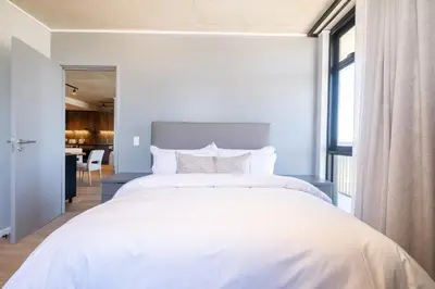 a white bed in a room with a large window at 311 Riverlands - Lux 2 Bedroom Apartment in Cape Town