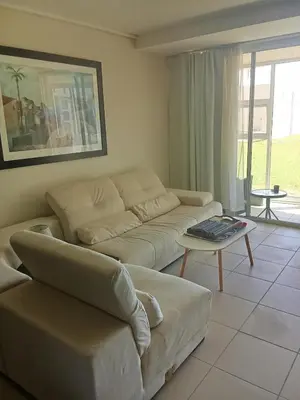a living room with a couch and a table at Spacious Beachfront 2bedroom apartment lagoon view in Cape Town