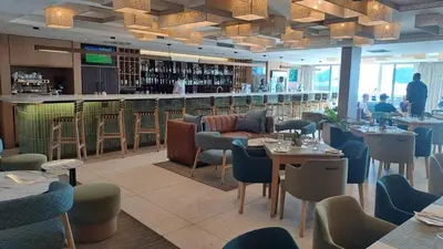 a restaurant with tables and chairs and a bar at Spacious Beachfront 2bedroom apartment lagoon view in Cape Town