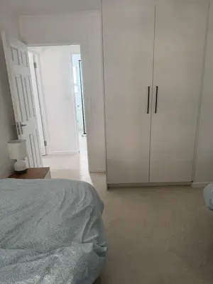 a white bedroom with a bed and white cabinets at Mountain View 2-Bedroom Home Near the Beach in Pringle Bay in Pringle Bay