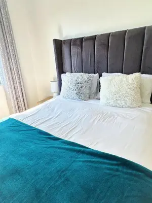 a bed with a blue blanket and pillows on it at Lux City Haven in Cape Town