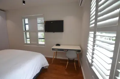 a bedroom with a bed and a desk and a tv at Just Joey Lodge in Stellenbosch
