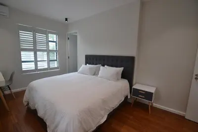 a bedroom with a bed with white sheets and a window at Just Joey Lodge in Stellenbosch