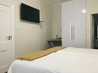 a bedroom with a bed and a flat screen tv on the wall at Just Joey Lodge in Stellenbosch