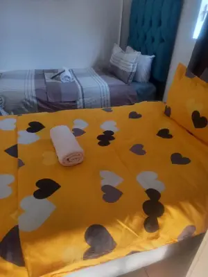 a bed with a yellow blanket with black and white mushrooms at MAREE LODGe GUEST HOUSE BELLEVILLE in Bellville