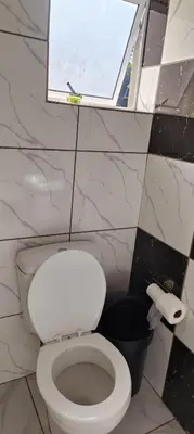 a bathroom with a white toilet and a window at MAREE LODGe GUEST HOUSE BELLEVILLE in Bellville