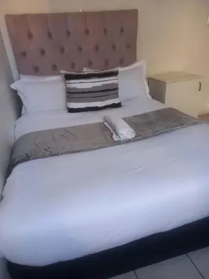 a white bed with a towel on top of it at MAREE LODGe GUEST HOUSE BELLEVILLE in Bellville