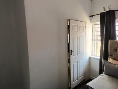 a bedroom with a door and a window at MAREE LODGe GUEST HOUSE BELLEVILLE in Bellville