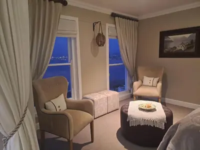a room with two chairs and a table and a bed at Boutique Inn - Serenity in Gordonʼs Bay