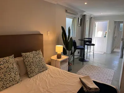 a bedroom with a bed and a table with a lamp at Secluded Silver Mile with solar back-up in Cape Town