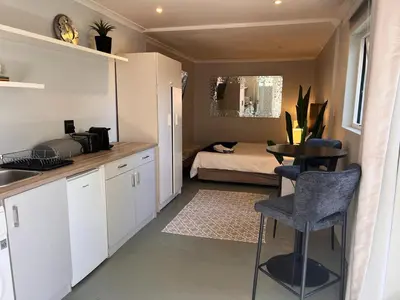 a kitchen with a table and a bedroom with a bed at Secluded Silver Mile with solar back-up in Cape Town